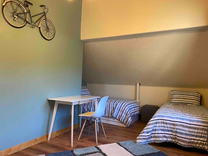 Twee slaapkamers met twee eenpersoonsbedden met een bureau. 