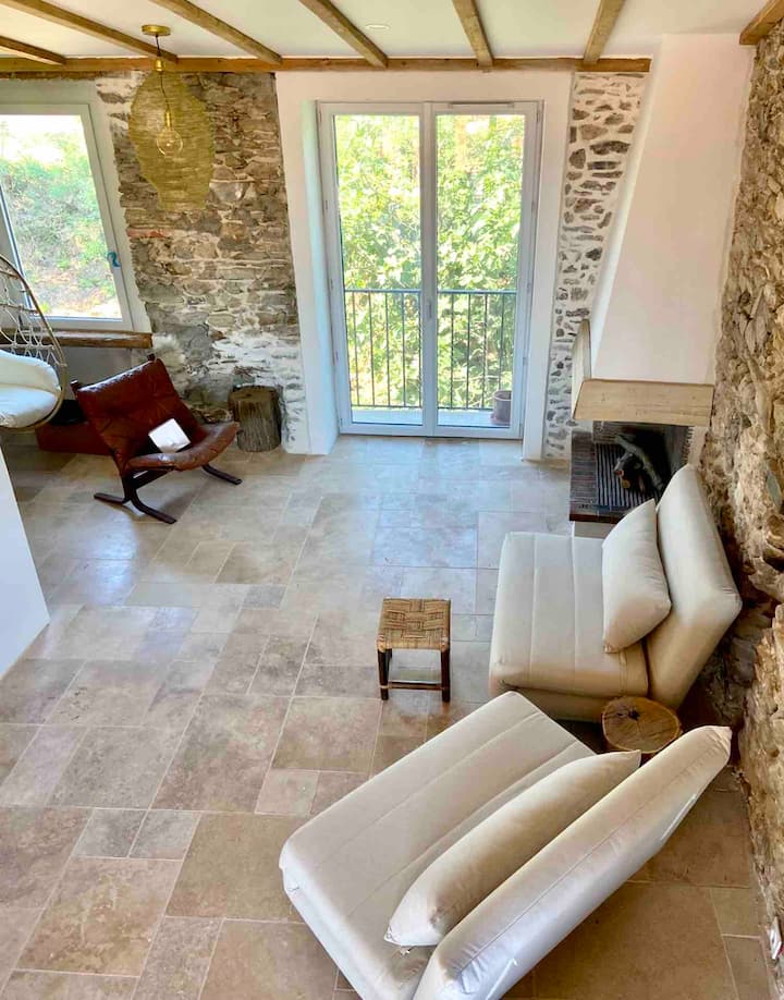 Sebule iliyo na kuta za mawe ya kale, sakafu ya travertine, mahali pa kuotea moto, vitanda viwili vya sofa.