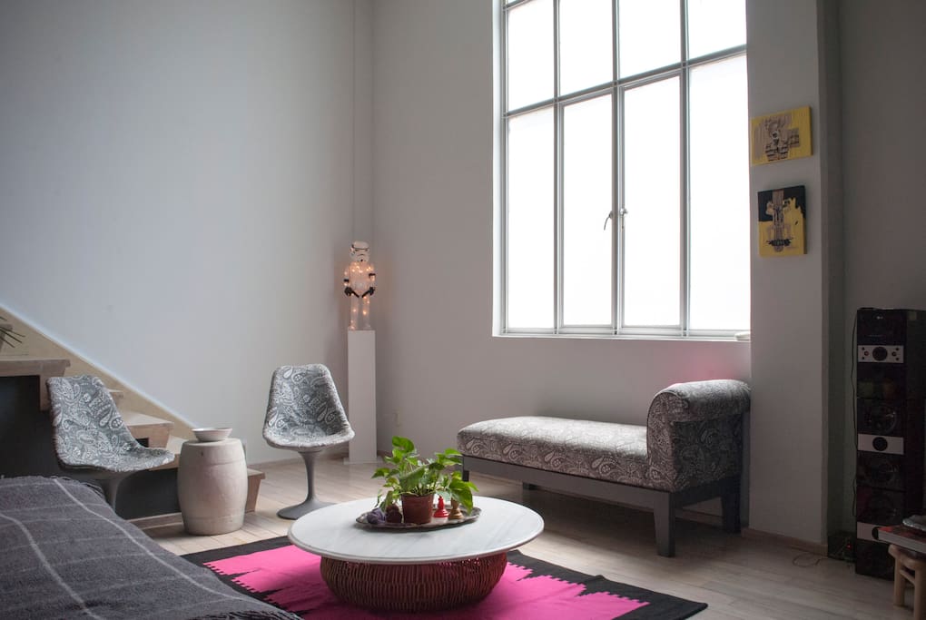 Estancia principal del apartamento, ambientado en tonos grises y duela de pino en lechereado blanco; decorado con arte contemporáneo y muebles de diseñadores mexicanos.