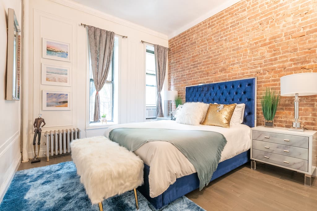 Top-Floor Master Bedroom outfitted with gorgeous decor and linens, with great sunlight, exposed brick and a beautiful view of the back yard patio