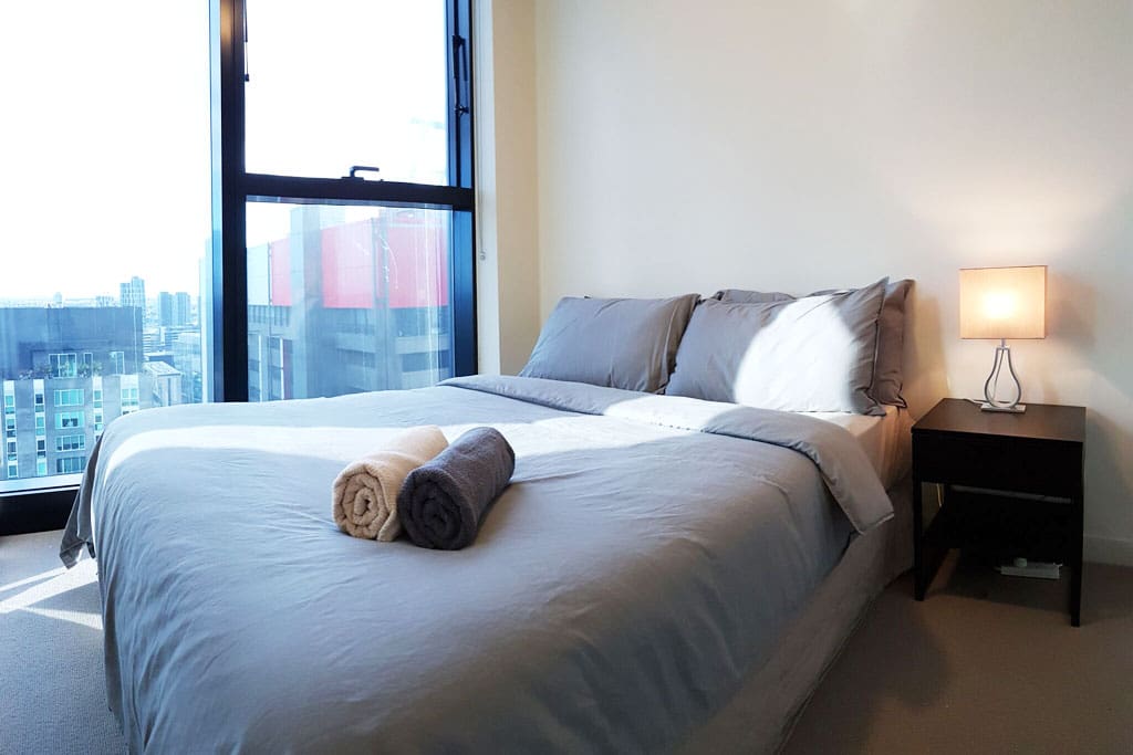 A bedroom with a queen sized bed & plush pillows.