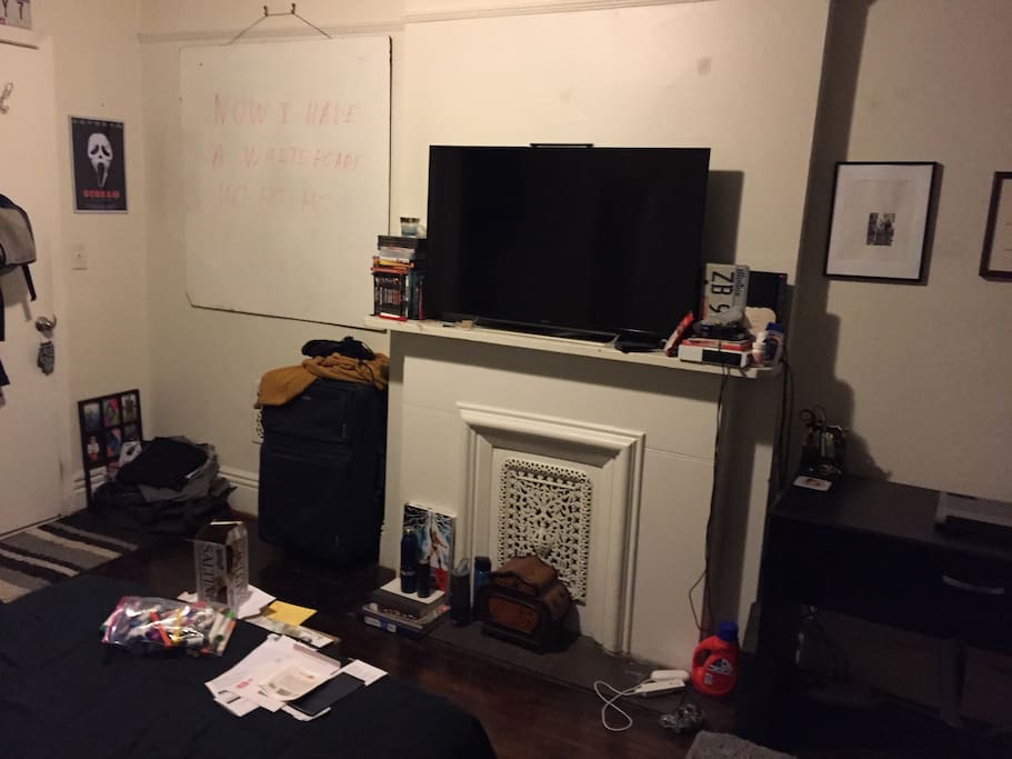 Door to the shared kitchen, large flatscreen TV with AppleTV, desk.