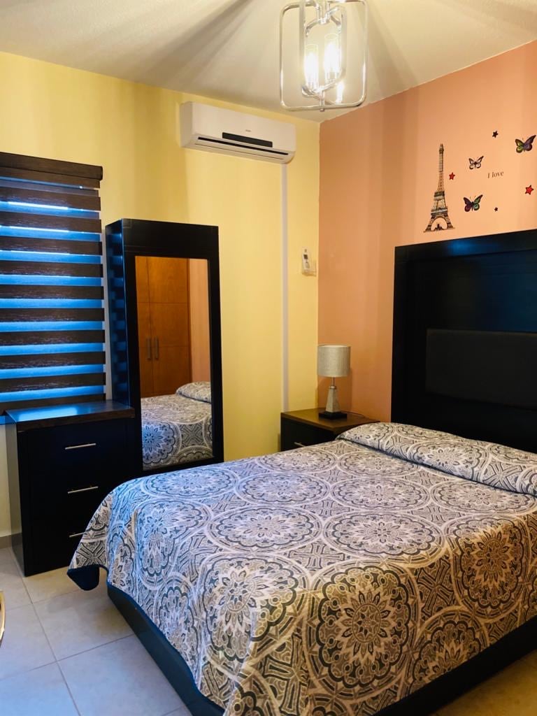 Schlafzimmer 2 verfügt über eine Kommode, einen Spiegel, eine Klimaanlage, einen Euro und ein Fenster mit Blick auf den Garten. 