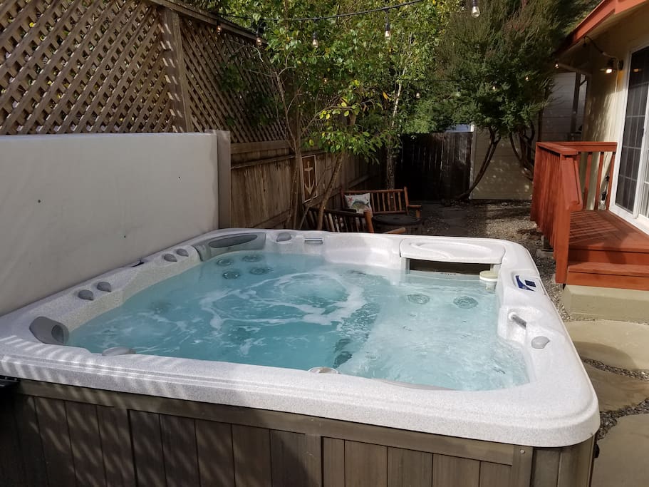 Luxurious hot tub in inviting garden accommodates 6+. Recliner seat with view of shady garden and fire table seating area