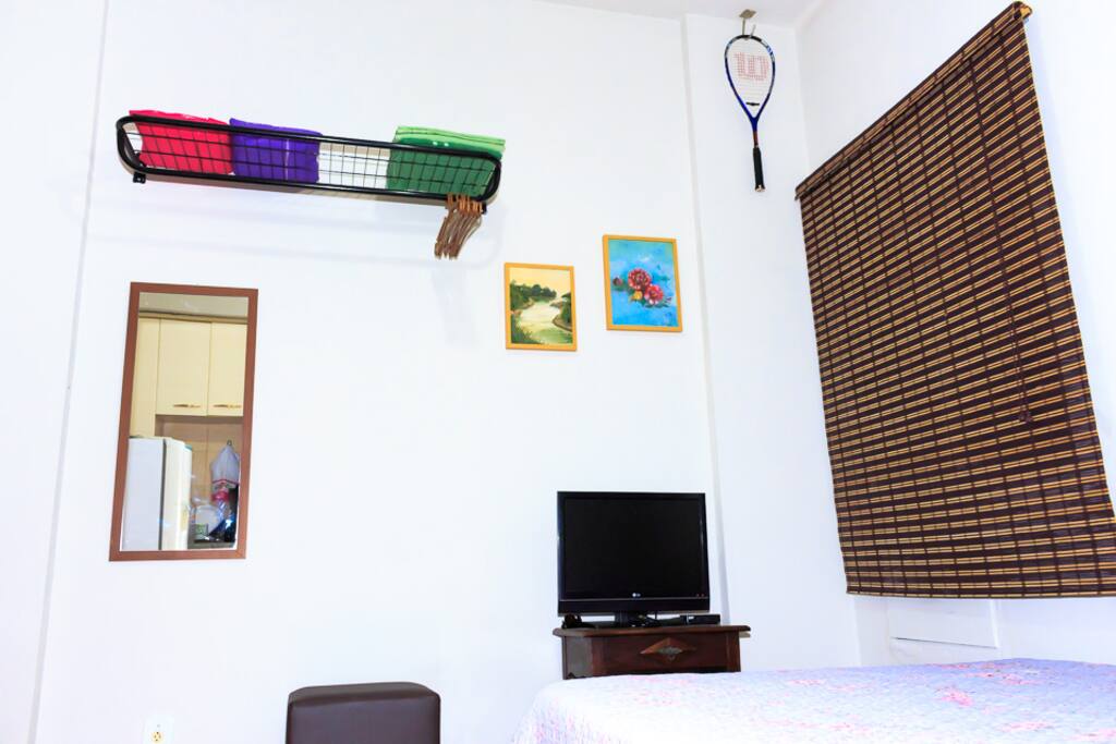 Tv a cabo, cabideiro, espelho e puffs.