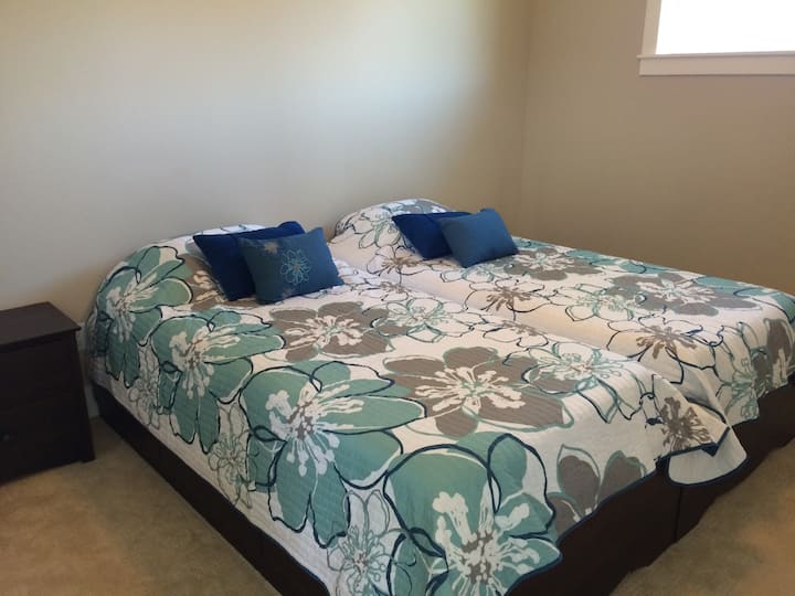 בחדר השינה בקומה העליונה יש שתי מיטות נפרדות ארוכות במיוחד.