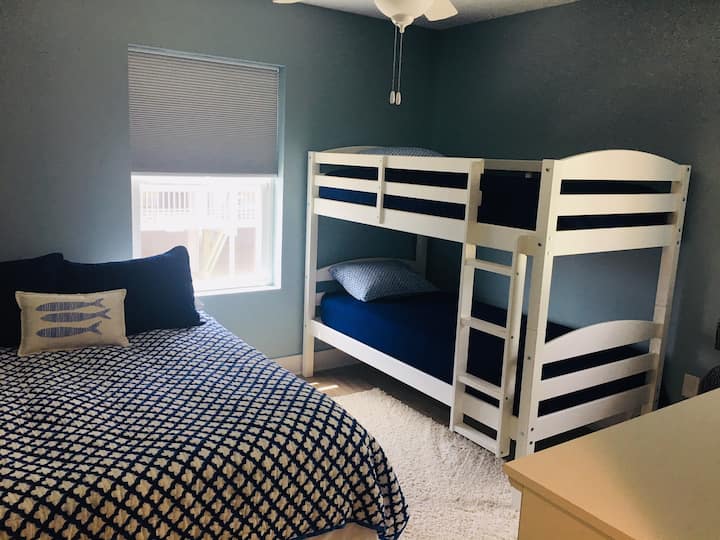 חדר שינה לאורחים עם מיטת קווין סייז ומיטות קומתיים.