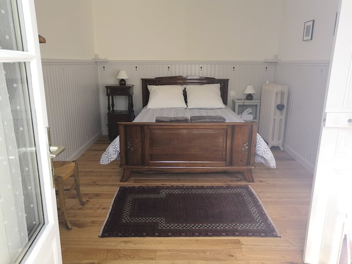 The main double bedroom with a standard double bed & central heating for winter days.  Newly renovated (2019) with handcrafted painted wooden paneling and local chestnut floor.  
The double doors, leading out into the cottage's garden, have shutters 