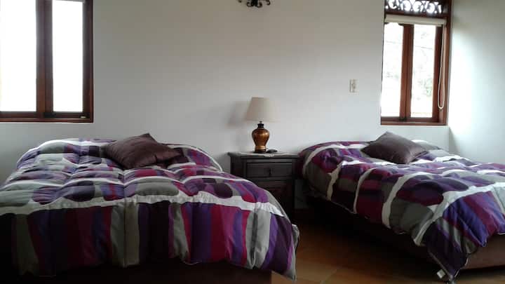 Quarto com 2 camas semi-duplas, TV, banheiro privativo,  varanda com vista para as montanhas e saída para o terraço