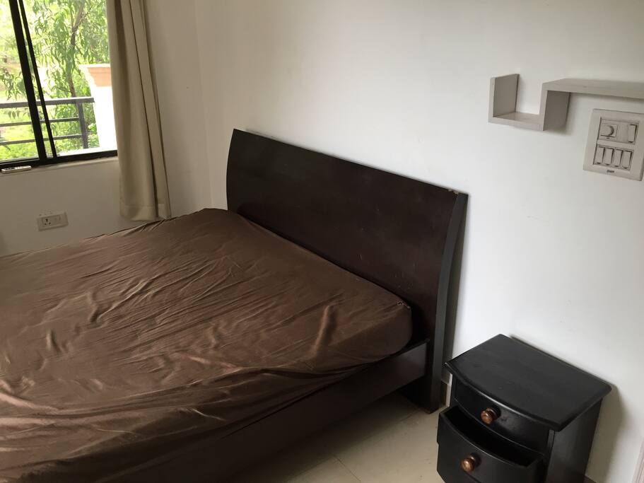 Bedroom with a private forest facing balcony, queen size bed, a large cupboard and shelf with books
