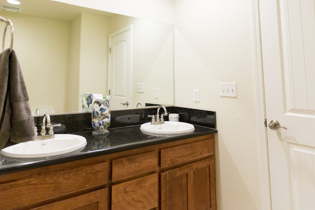 Lots of space in the bathroom for two, featuring a vanity sink with granite countertops, fresh towels and an array of soaps and shampoos.