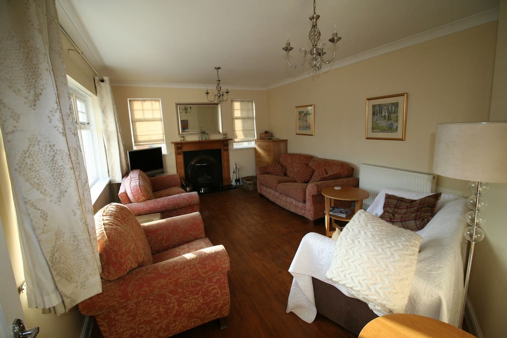 The sitting room, with three comfortable sofas plus armchair, TV and open fire