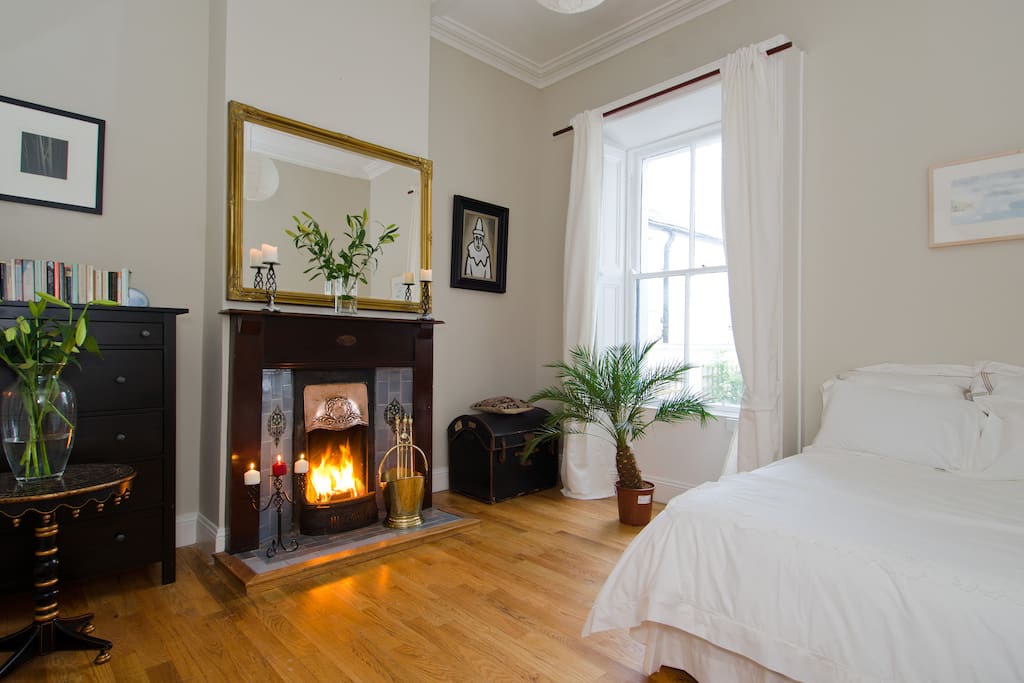 Spacious double bedroom with feature fireplace and high ceilings