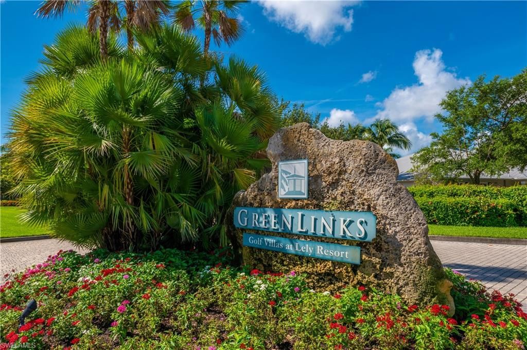 An entrance sign for GreenLinks at Lely Resort is showcased, surrounded by lush tropical foliage and colorful flowering plants. The sign features the name 'GreenLinks' prominently displayed, set against a backdrop of blue skies and scattered clouds.