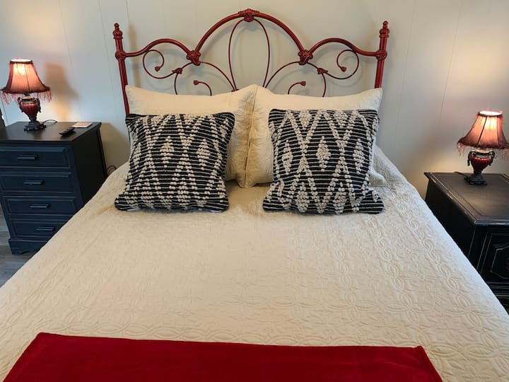 Downstairs,  Fleur de Lis Bedroom, includes comfortable queen bed, mounted streaming TV, storage and ceiling fan