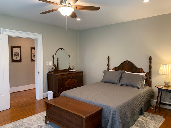 The Travel Room features a large queen bed, victorian dresser and wardrobe, as well as a steamer trunk and hand luggage from years and travels past.