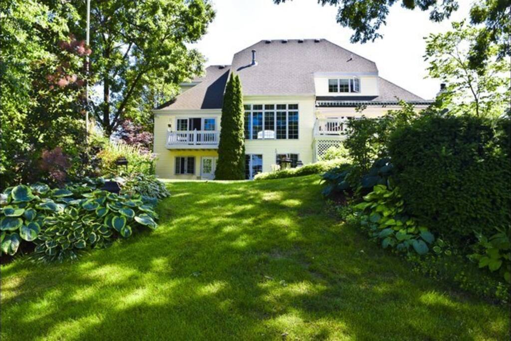 Waterfront large home backyard view with pontoon boat, fire pit lawn chairs, kayaks, and ping pong table and more!