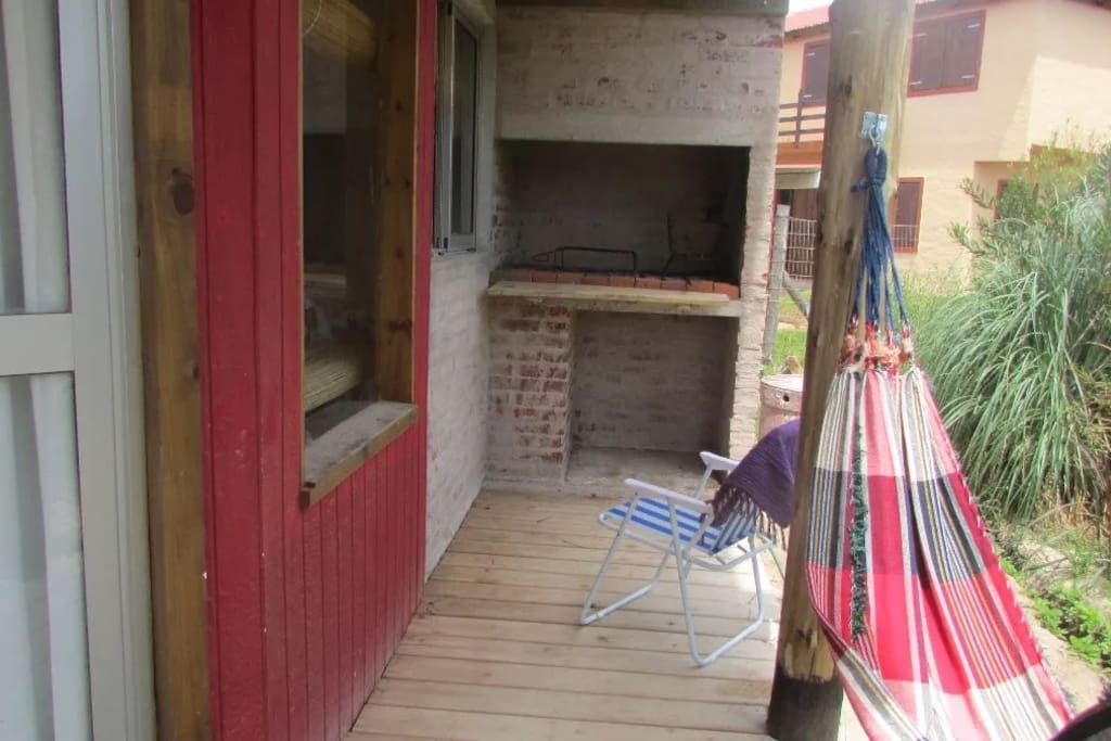 Deck lateral con parrillero techado junto a la cocina y a su ventana.