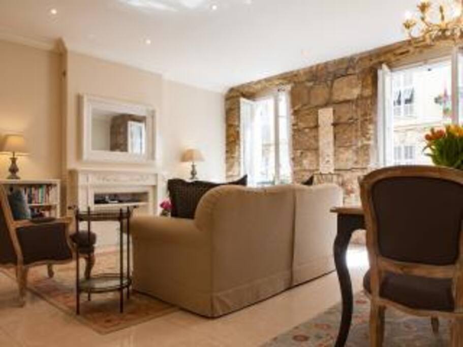 LIVING AREA/DINING AREA
The original stone walls of the living and dining areas as well as the decoration with historic bas-reliefs from a Spanish church make the heart of this apartment special and warm.
The living room is spacious and relaxing. It is comfortable for reading, catching up on email, or watching the wide screen TV. If you prefer a quiet chat with friends and family, the television won't intrude at all as it is concealed by an elegantly framed mirror above the fireplace when not illuminated (see photo). Wool carpets make the rooms extra cozy.
The dining area easily accommodates six or even eight!