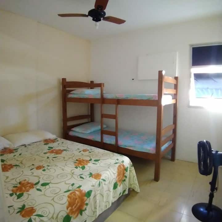 Habitación con una cama plegable y una cama doble. Ventilador de techo y ventana.