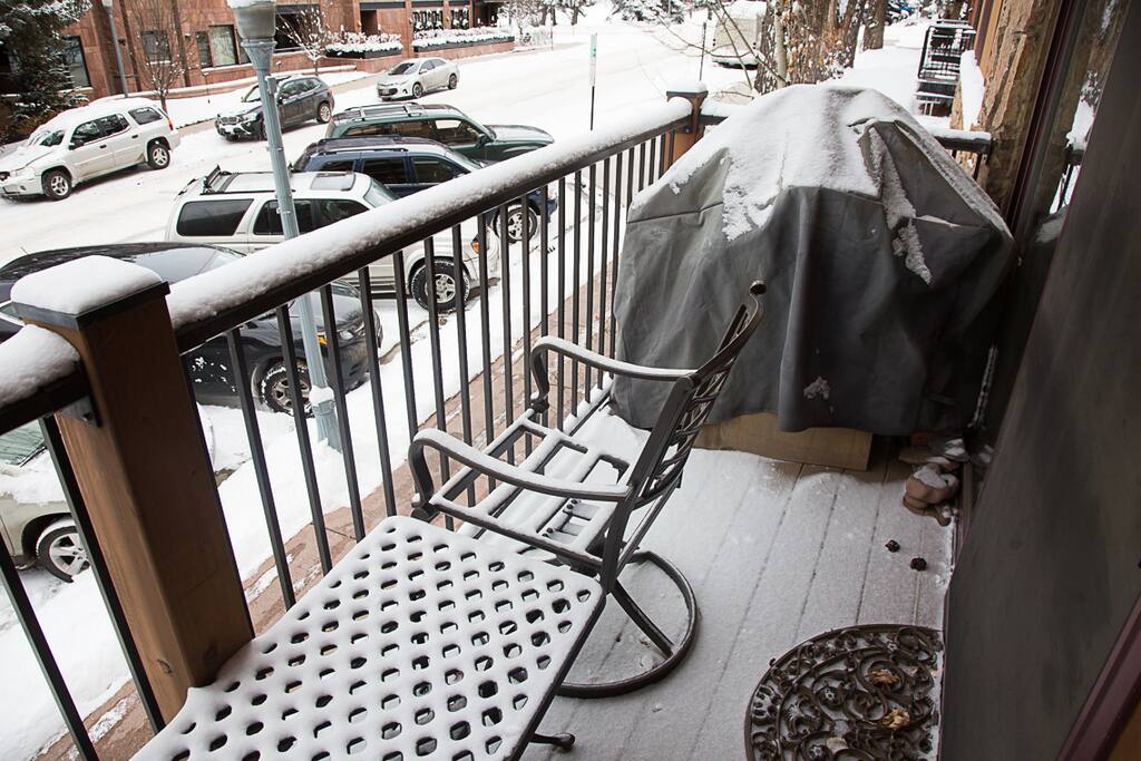 A BBQ grill and patio seating on the balcony
