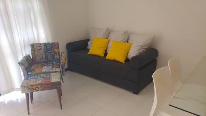 غرفة معيشة بسرير أريكة وتلفزيون ومروحة تيتو.