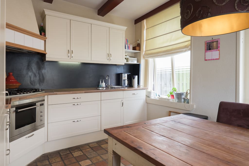Woonkeuken met combi magnetron/grill/bakoven, vaatwasser, koel/vriescombinatie, espressomachine, waterkoker en melkopschuimer.