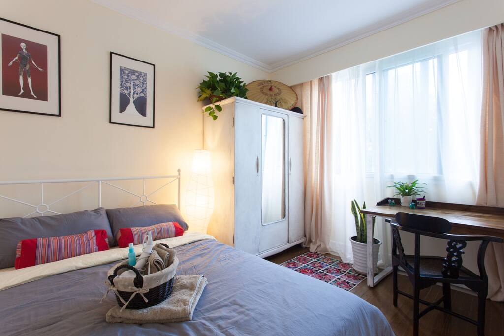 Guest room with a queen size bed, a large wooden desk and a vintage style cupboard.