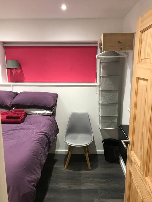 High bed with lots of storage for large bags underneath, hangers and boxes for clothes, wall mounted collapsible desk for laptop working, guest towels provided.