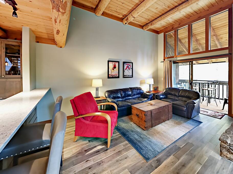 Seating for 6 in the living area, furnished with leather sofas and a red accent chair.