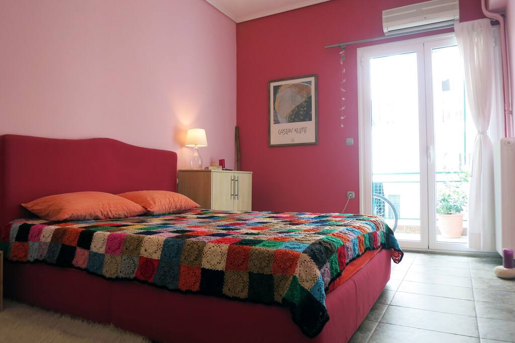 Bedroom with a small balcony, carpeted during wintertime, with a king size bed, a closet and a shoekeeper, a radiator and an a/c