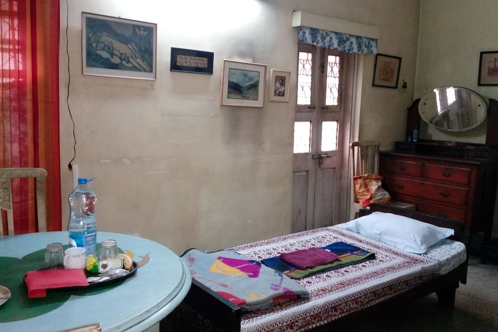 Large, spacious room with single bed, dresser with mirror, and multipurpose table.