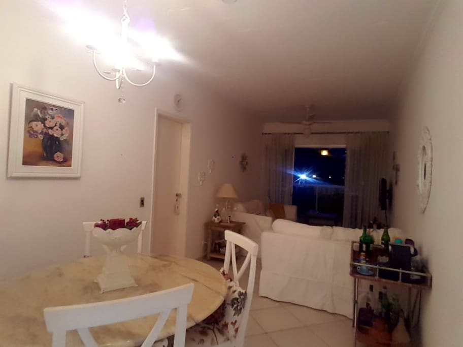 Visão da sala de jantar, living e varanda ao fundo. A direita, aparador com a máquina de café Nespresso.