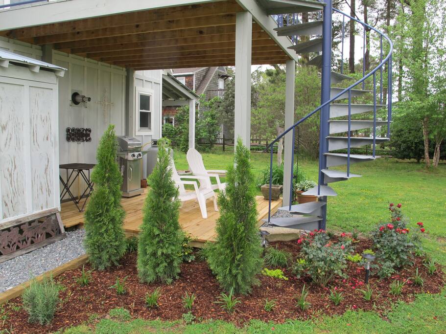 Lower deck with chairs and a grill. Outdoor shower to the left.