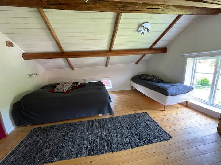 Dormitorio, arriba. Una habitación espaciosa con cama de matrimonio, cama individual y almacenamiento. Nota: Baja altura del techo en los extremos de la habitación.