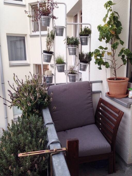 Grüner Balkon mit Sessel und Kräutergarten