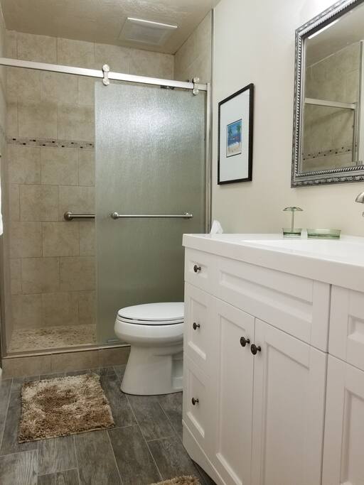 Upgraded bathroom with walk in shower, tile floor, vanity and lighting