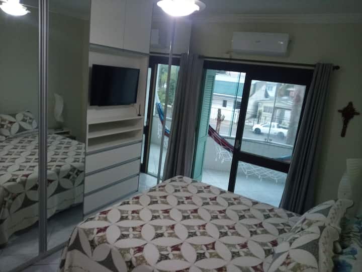 Soba u apartmanu s klima-uređajem, stropnim ventilatorom, bračnim krevetom, pametnim televizorom i balkonom s visećom ležaljkom .