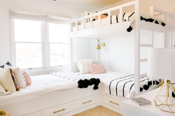 חדר המיטות המותאם אישית מואר, מואר ונוח למבוגרים ולילדים כאחד. הוא כולל מיטה זוגית ושתי מיטות נפרדות. יש שפע של מקום אחסון ועיצוב אווירה - עם תמונות של צלמים מקומיים של אאוטר בנקס.