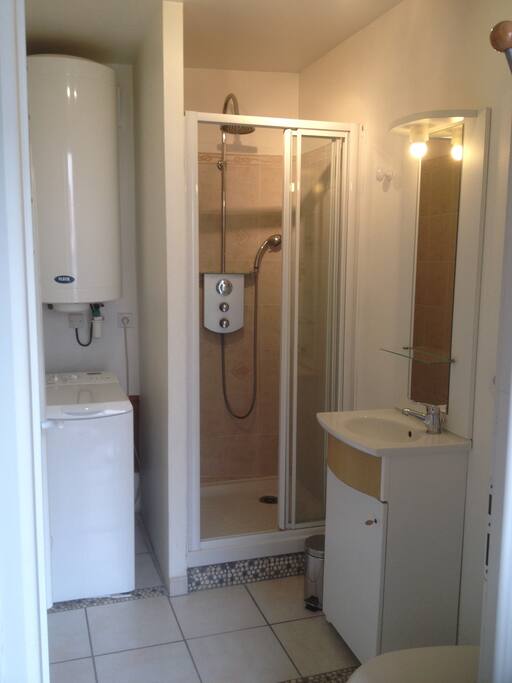 Salle d'eau avec douche double pommeau, lave linge et wc.