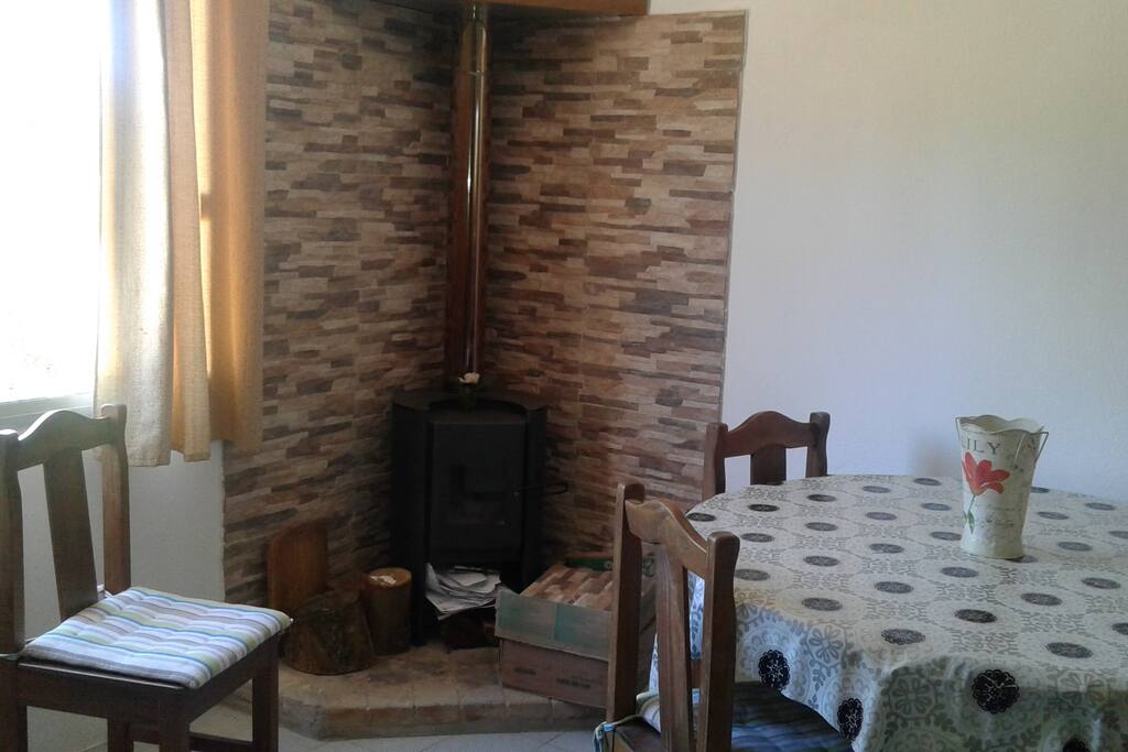 Comedor con estufa a leña, mesa para 4 personas. Espacio con ventana.