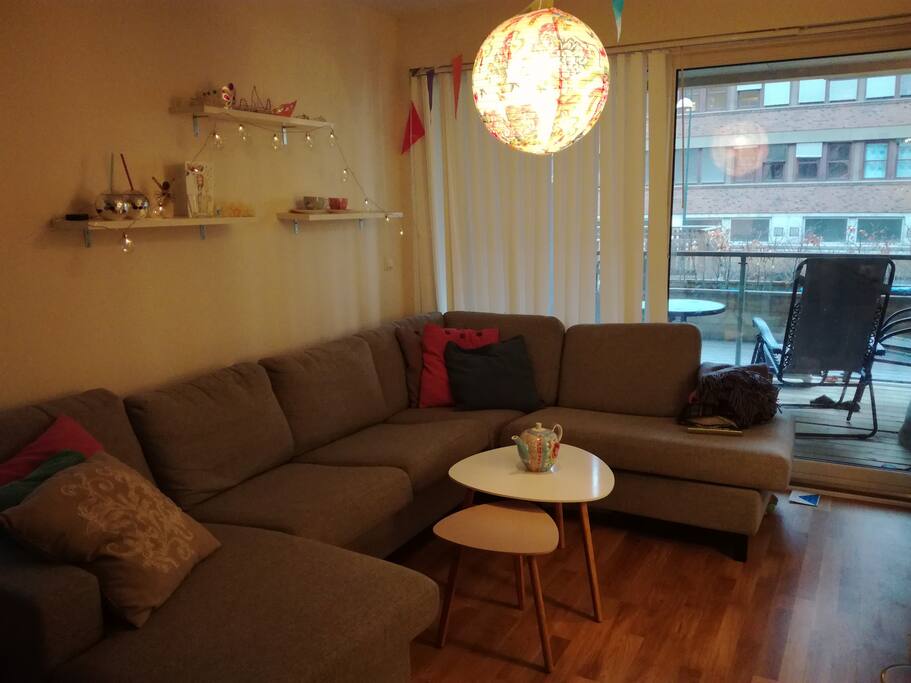 Stue med stor sofa og store glassvindu ut mot koselig balkong
