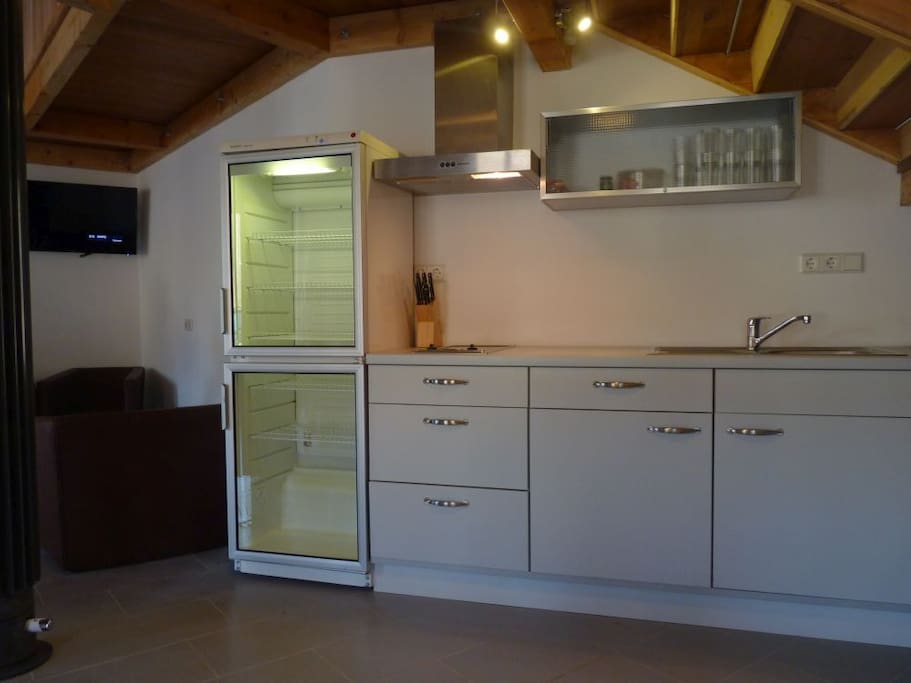 Die Küchenzeile ist modern und mit 2er Cerankochfeld, Abzugshaube, großen Glas-Kühlschrank, Gefrierschrank, Gewerbe-Geschirrspüler sowie Mikrowelle, Kaffeemaschine, Toaster und Wasserkocher, ausreichendem Geschirr, Besteck und Kochutensilien voll ausgestattet.