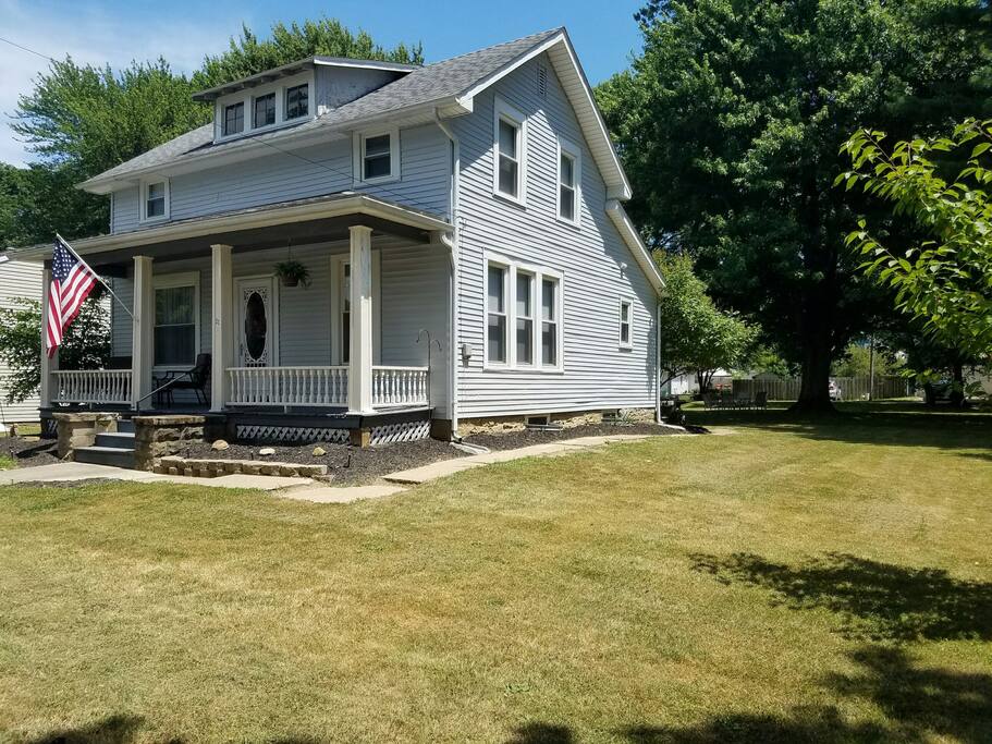 Large front porch with 2 chairs and a table