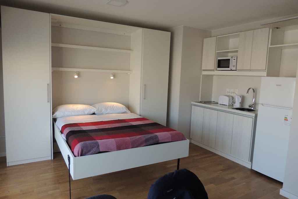 Cama abierta con ropa de cama nueva, cómodo colchón y almohadas