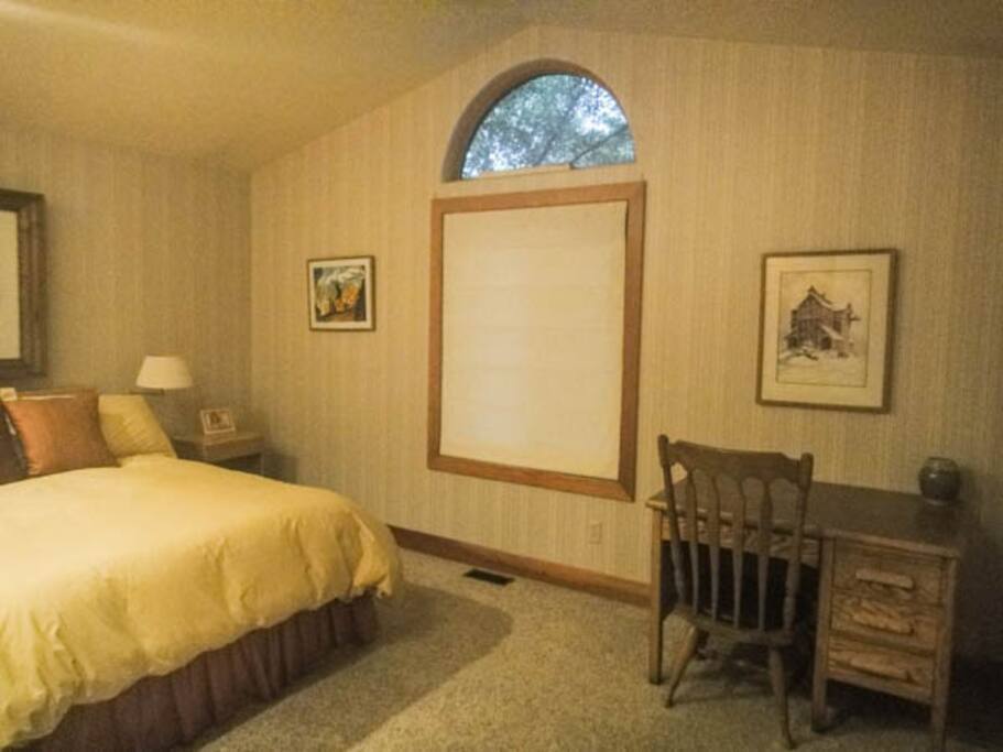 Bedroom with desk, next to private bath with shower/tub