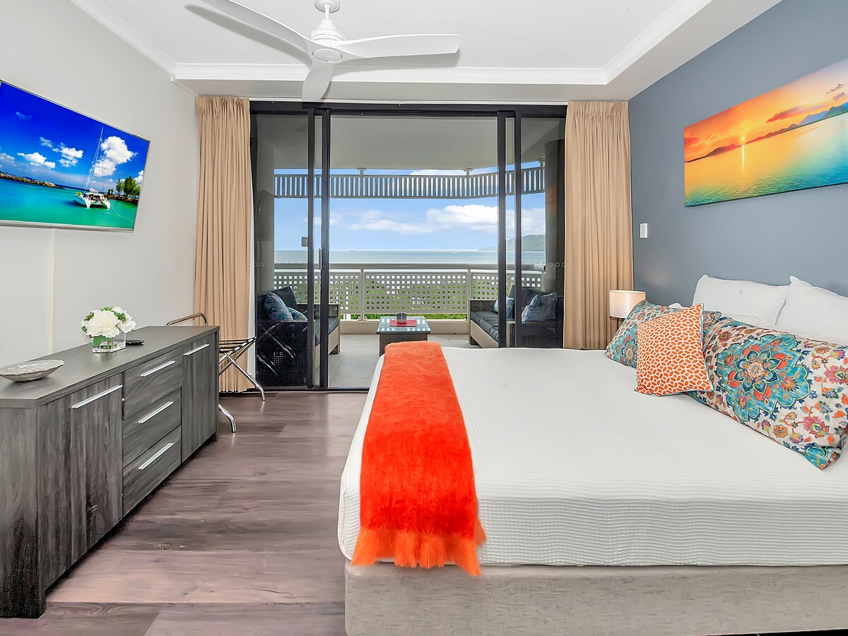 El dormitorio principal está bellamente equipado con una cama tamaño queen, TV montada en la pared y acceso directo al balcón. 