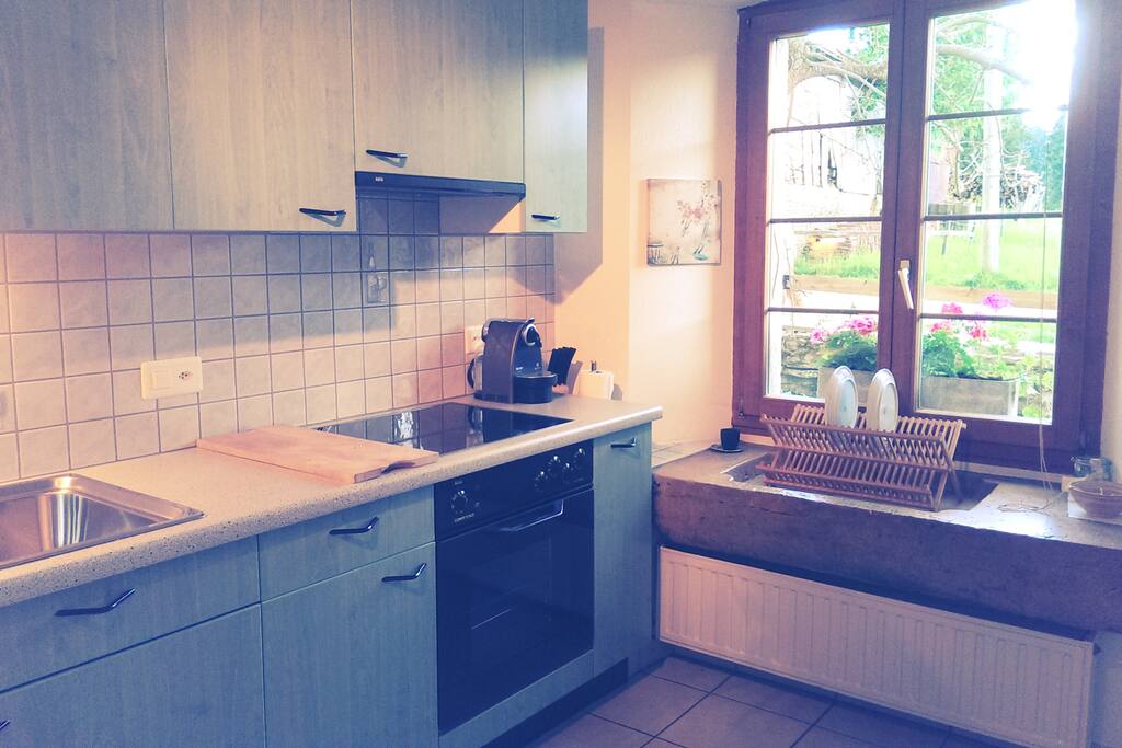 Cuisine agencée avec lave-vaisselle et machine à café (système Nespresso), vue sur les pâturages des Franches-Montagnes.