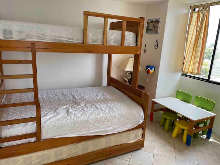 Litera con dos colchones matrimoniales y una cama individual. Mesa para niños y taburetes. Bunk bed con dos camas queen y una twin. Mesa de niños con sillas. Muy acogedor y funcional.