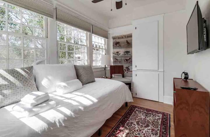 غرفة نوم مريحة تضم سريرين صغيرين مع تلفزيون روكو وكتب وخزانة ملابس. ظلال التعتيم على النافذة. 